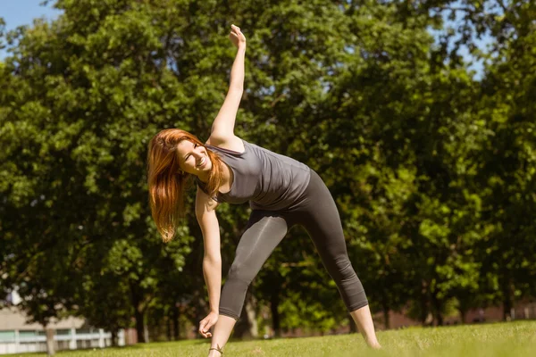 Ganska atletisk rödhårig stretching i park — Stockfoto