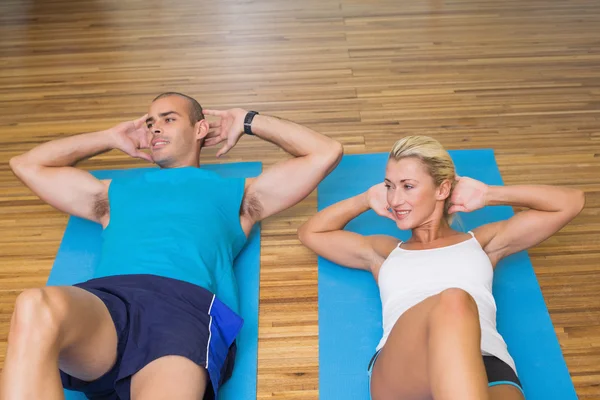 Sporty couple doing abdominal crunches at fitness studio — Stock Photo, Image