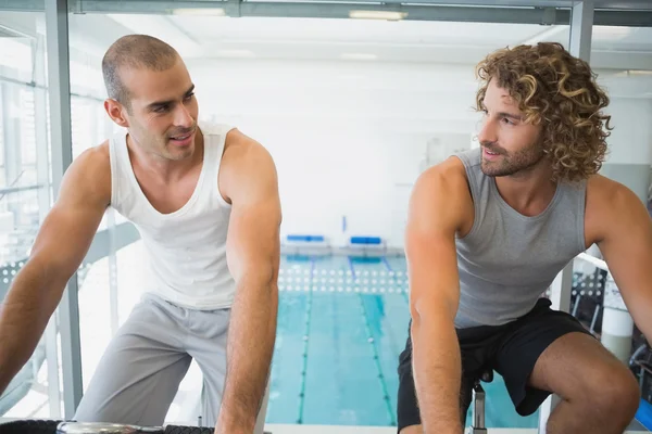 Ajustar a los hombres que trabajan en bicicletas estáticas en el gimnasio — Foto de Stock