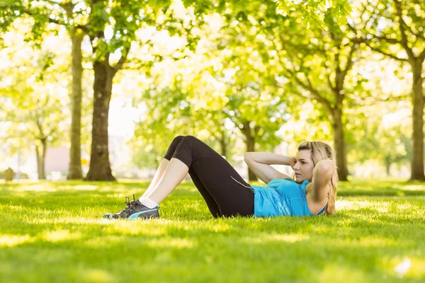 Ajuste rubia haciendo sit ups en el parque — Foto de Stock