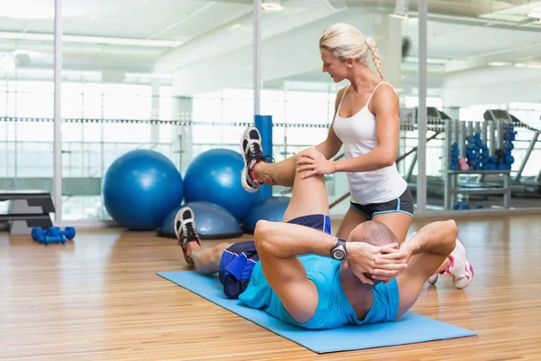 Tränare hjälpa mannen med övningar på fitnesstudio — Stockfoto