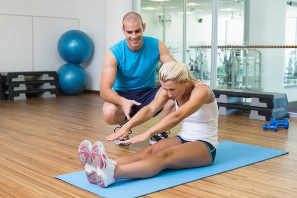 Trainer assisting woman with exercises at fitness studio — Stock Photo, Image
