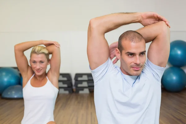 Pareja estirando las manos detrás de la espalda en clase de yoga —  Fotos de Stock