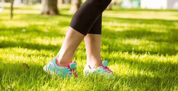 Femme en chaussures de course marchant sur l'herbe — Photo