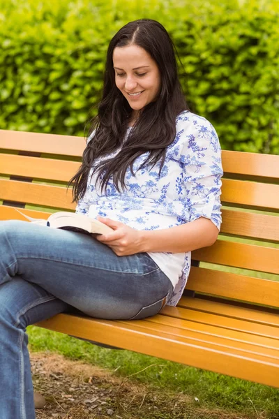 Brune souriante assise sur un banc de lecture — Photo