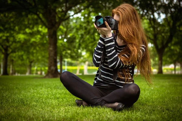 Çimenlerin üzerinde oturan kadın fotoğrafçı — Stok fotoğraf