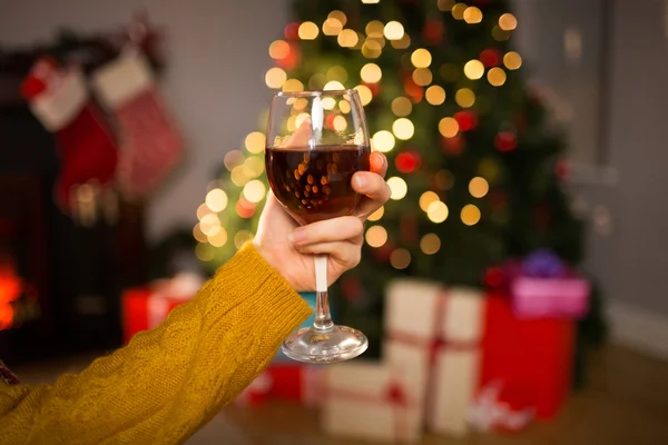 Mujer sentada en un sofá mientras sostiene una copa de vino tinto — Foto de Stock