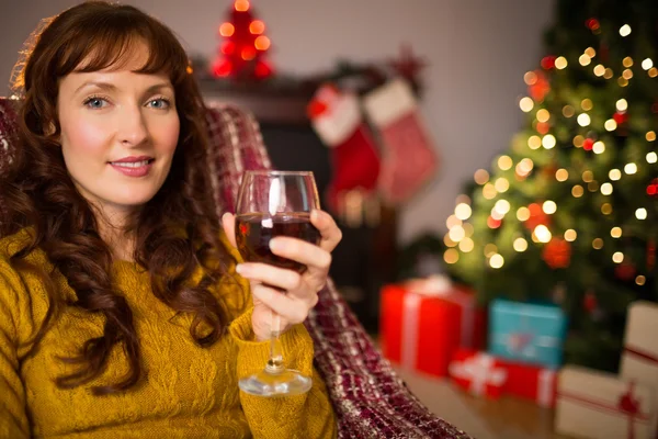 Femme assise sur un canapé tout en tenant un verre de vin rouge — Photo
