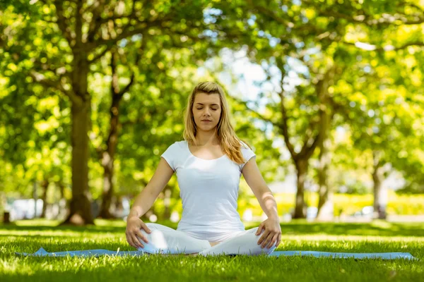 Passen blonde zitten in lotus pose in het park — Stockfoto