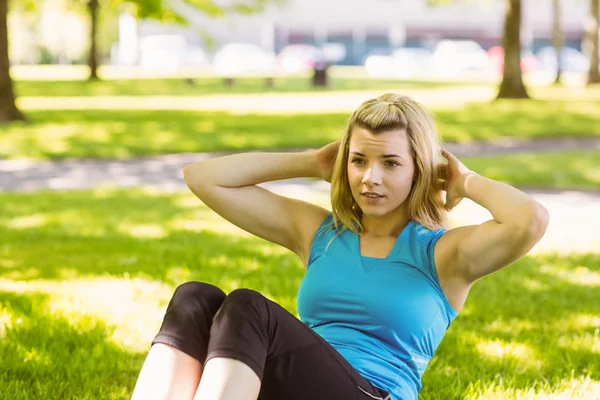Fit blonde doing sit ups in the park — Stock Photo, Image