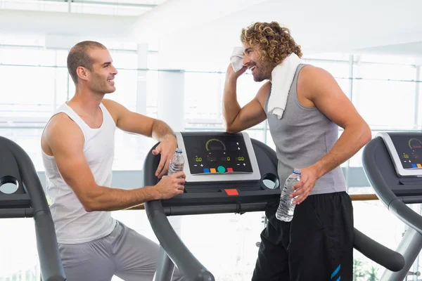 Entrenador sonriente hablando con el hombre en forma en el gimnasio — Foto de Stock