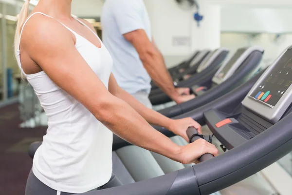 Side view mid section of couple running on treadmills at gym — Stock Photo, Image