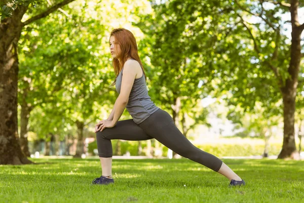 Ganska atletisk rödhårig stretching i park — Stockfoto