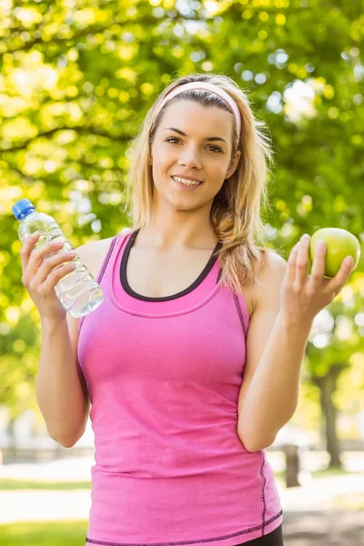 Ajuste rubia celebración de agua y manzana —  Fotos de Stock