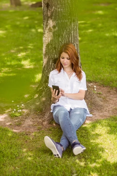 Pretty redhead text messaging on her phone — Stock Photo, Image