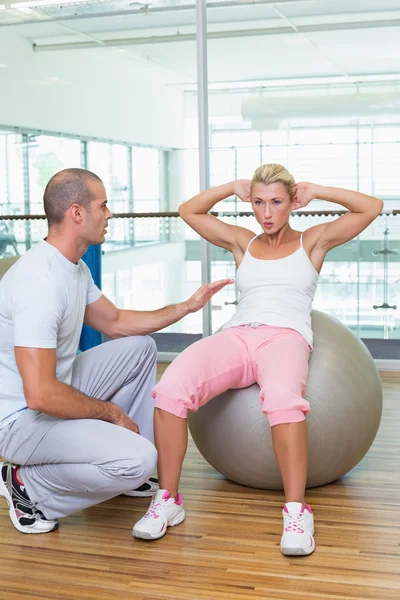 Tränare hjälpa kvinnan med buken crunches på gym — Stockfoto