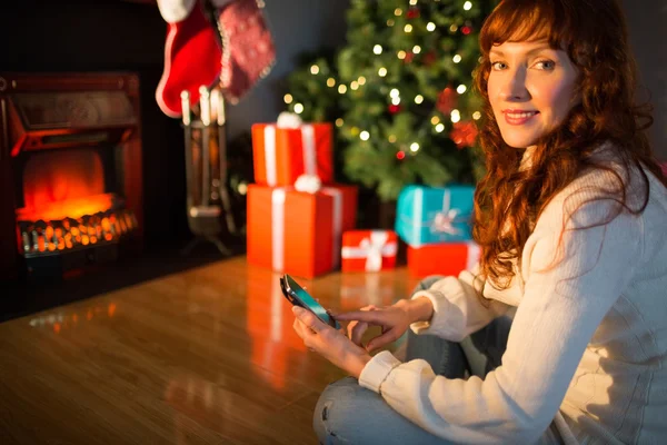 微笑在圣诞节时使用智能手机的红发女郎 — 图库照片