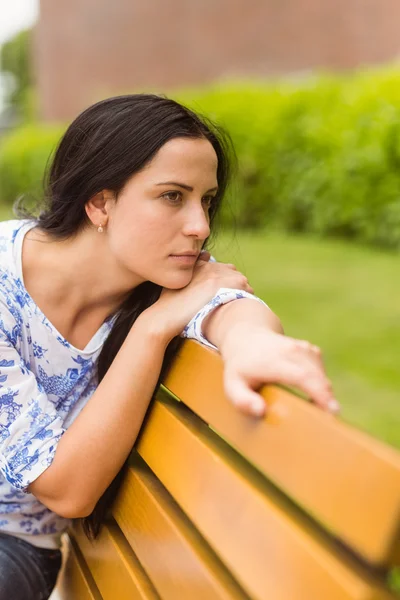 Brunette thinking and sitting on bench — Stock Photo, Image