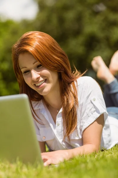 Mooie roodharige gelukkig en liggen met haar laptop — Stockfoto