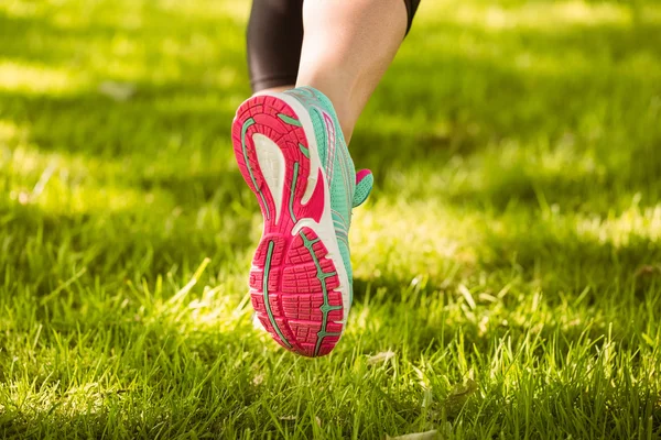 Vrouw in loopschoenen uitgevoerd op gras — Stockfoto