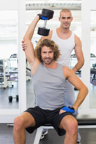 Entraîneur assistant jeune homme avec haltère dans la salle de gym — Photo