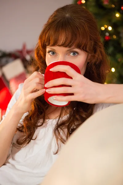 Pretty redhead sitting on couch drinking hot chocolate — Stock Photo, Image