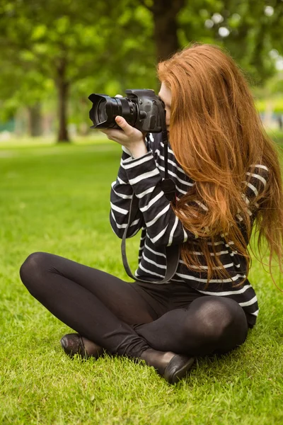 Vrouwelijke fotograaf zittend op het gras — Stockfoto