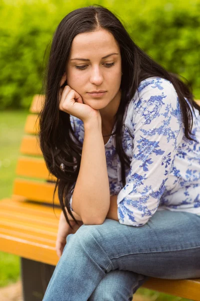 Thoughtful casual brunette sitting on bench — Stock Photo, Image