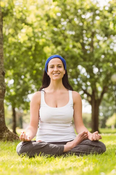 Smiling brunette in lotus pose on grass — Stock Photo, Image