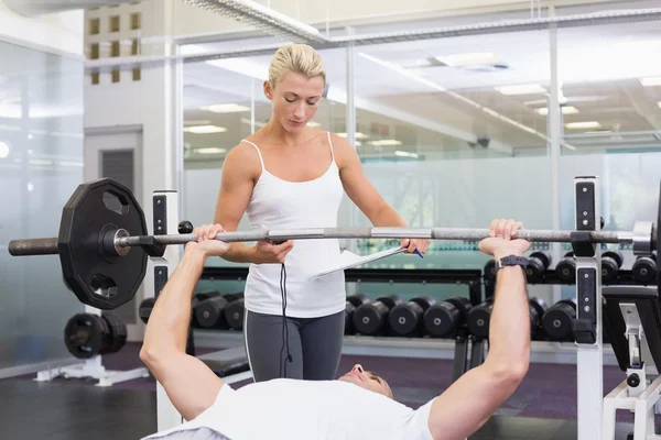 Allenatore che aiuta l'uomo a sollevare il bilanciere in palestra — Foto Stock