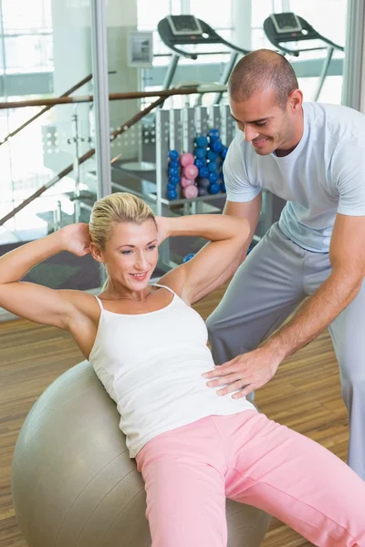 Tränare hjälpa kvinnan med buken crunches på gym — Stockfoto