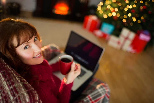 Piękny rudy trzymając kubek gorącego napoju i laptopa — Zdjęcie stockowe