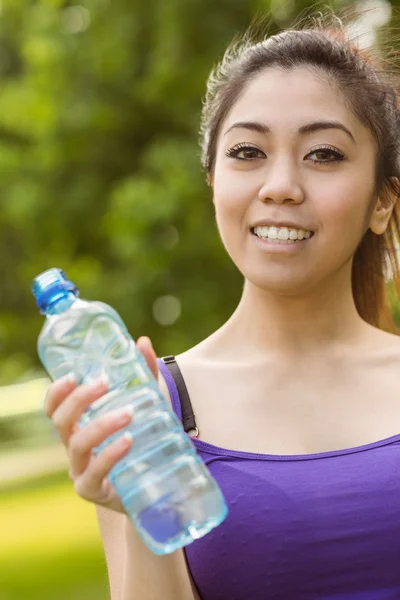 Женщина держит бутылку с водой в парке — стоковое фото