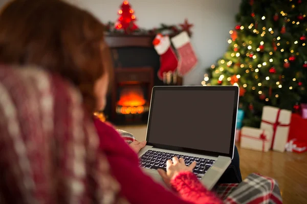 Rödhårig maskinskrivning på laptop på fåtöljen vid jul — Stockfoto