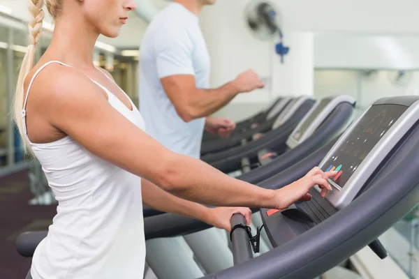 Sidoutsikt mot mitten av delen av par körs på löpband på gym — Stockfoto