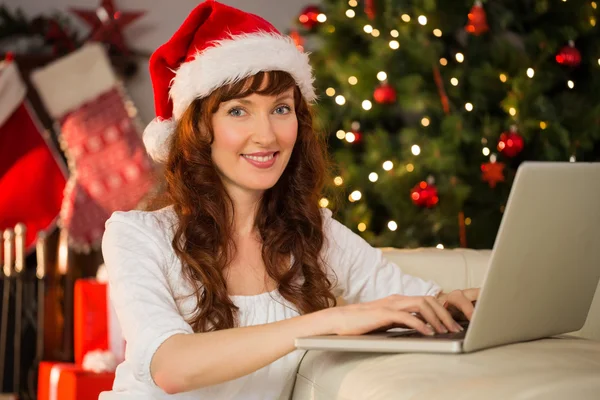 Redhead in kerstmuts met behulp van laptop op de Bank — Stockfoto