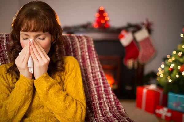 Woman sitting on sofa and blowing her nose at christmas — Stock Photo, Image