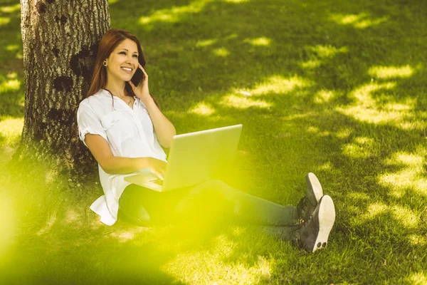 Ziemlich rothaarig am Telefon mit ihrem Laptop — Stockfoto