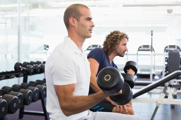 Vista lateral de los hombres haciendo ejercicio con pesas en el gimnasio — Foto de Stock