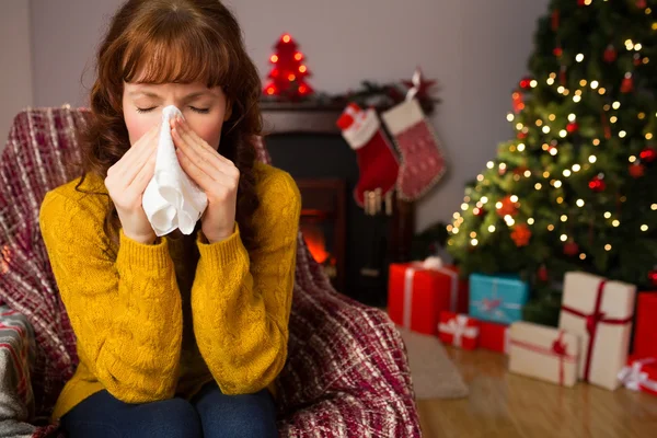 Kanepede oturan ve burnunu Noel'de üfleme kadın — Stok fotoğraf