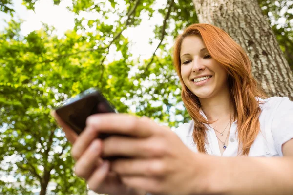 Mensagens de texto ruiva bonita em seu telefone — Fotografia de Stock