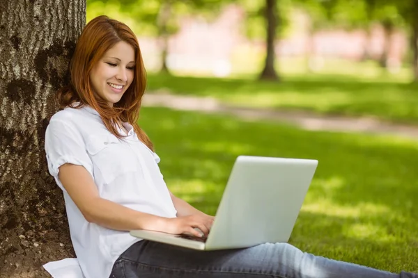 Söt rödhårig sitter med sin laptop — Stockfoto