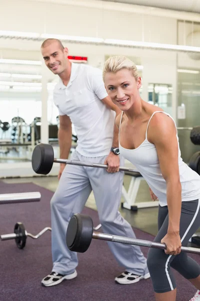 Sporty young couple lifting barbells in gym — Stock Photo, Image