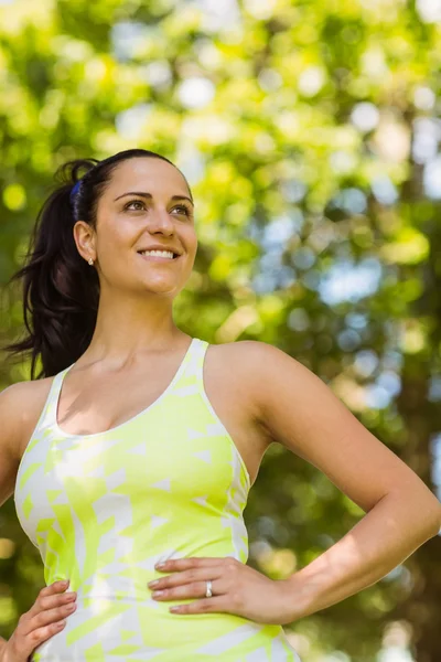 Lachende brunette in sportkleding met haar handen op de heupen — Stockfoto