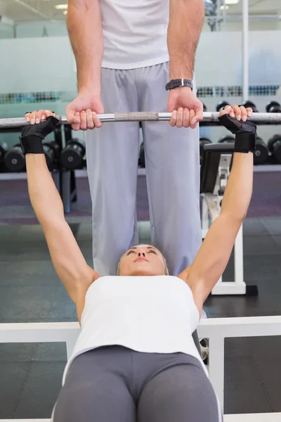 Formateur aidant femme avec haltère de levage dans la salle de gym — Photo