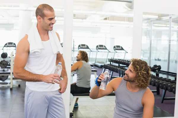 Entrenador sonriente hablando con el hombre en forma en el gimnasio — Foto de Stock