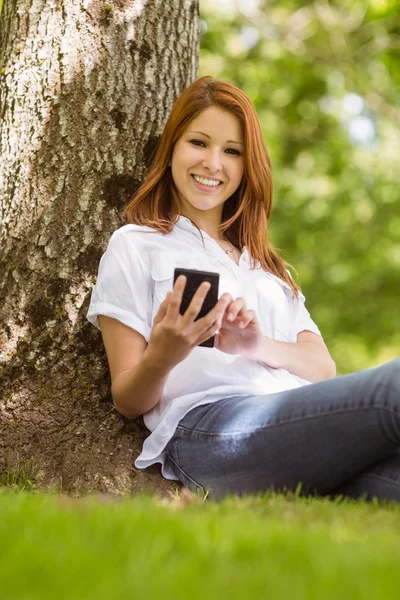 Hübscher Rotschopf lächelt und hält ihr Handy — Stockfoto