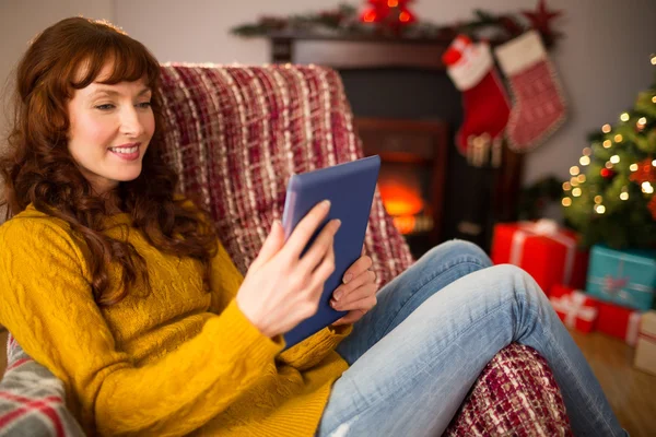 Pelirroja sentada en el sofá usando tableta en Navidad —  Fotos de Stock