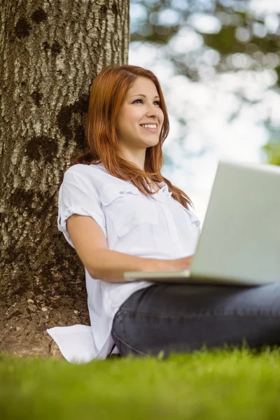 Pěkná zrzka usmívající se její laptop — Stock fotografie