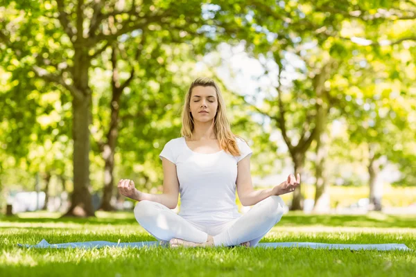 Passen blonde zitten in lotus pose in het park — Stockfoto